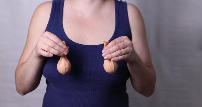 A woman aesthetically and delicately demonstrates the aging process and sagging bust in connection with feeding a child and age-related changes. High quality 4k footage