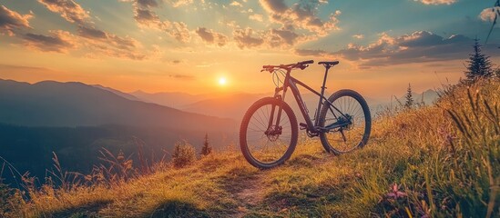 Fototapeta premium A mountain bike silhouetted against a stunning sunset in the mountains.