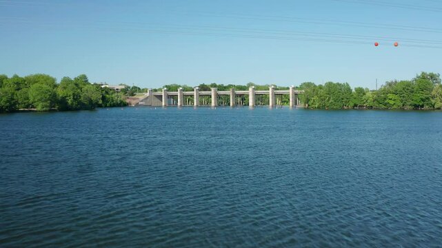 Drone travels just above the water's surface towards a dam in Austin, Texas