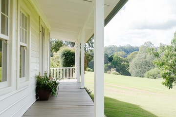 Fototapeta premium Sunny porch with lush greenery and rolling hills view on bright morning