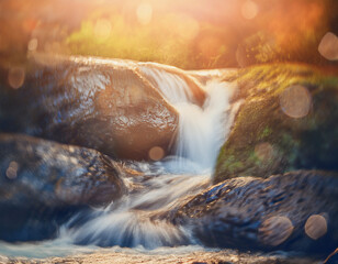 渓流や滝の勢いに合わせて明るい光が渦巻き、自然の力強さを象徴する　対照的な色彩が、自然のエネルギーと視覚的なダイナミズムを感じさせる背景イメージ