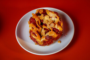 Red cake with almond topping on white plate with red background