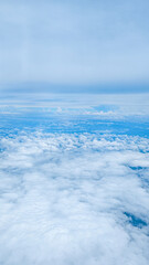 Aerial view of fluffy white clouds, captured from an airplane at high altitude. Scene for advertising, travel, aviation, exploration, nature, meteorology. Beautiful blue sky background