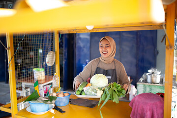 A cheerful vendor showcases fresh, vibrant vegetables at her colorful market stall