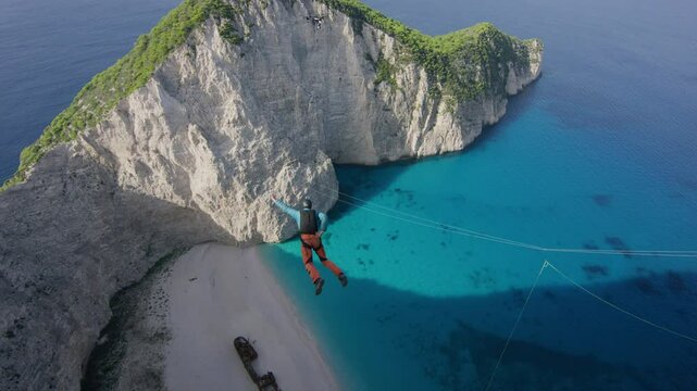 Majestic, cinematic shot of man parachuting off Greece cliffside - slow motion, high shot