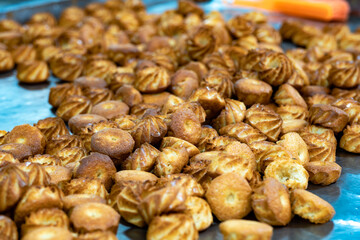 Close-up of golden-brown pastries fresh from the oven, displayed in abundance, highlighting their...