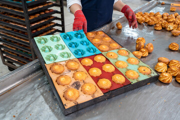 Bakery worker preparing fresh pastries using colorful silicone molds on a clean industrial workspace. High-quality food production.