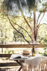 Fototapeta premium Open book and wine on rustic table under trees for outdoor relaxation and leisure