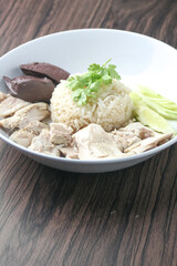 Hainanese chicken rice, steamed chicken rice served on a wooden table.