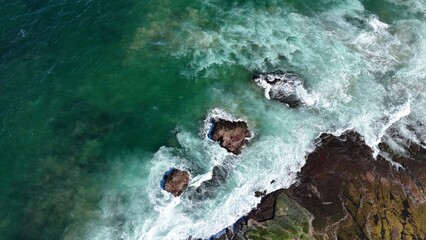 Fototapeta premium Drone shot aerial view of waves crashing onto rocks near a beach in Australia in summer 