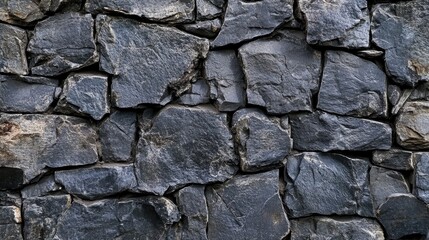 Obraz premium Black anthracite stone wall texture featuring irregular, rough stones arranged in a panoramic view, ideal for backgrounds and structural design needs.