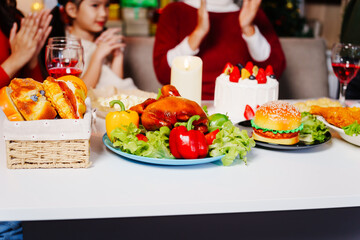 A loving family gathers at home for a Christmas party with parents, children, and grandparents. They celebrate Christmas and New Year joyfully, sharing wine, food, drinks, and exchanging gifts