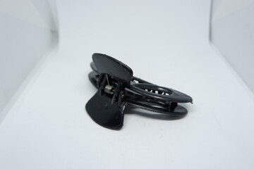 A close-up of a black plastic hair clip against a white background. Ideal for hair styling, fashion accessories, or beauty products. Minimalistic and simplistic in design.