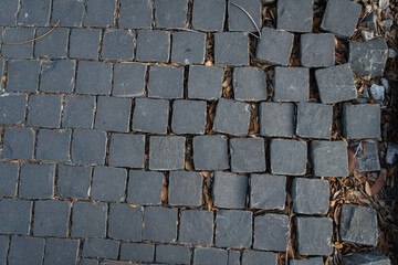A close-up of cobblestones arranged in a grid pattern, gradually dislodging and scattering towards the right side. Perfect for illustrating themes of urban decay and natural wear.
