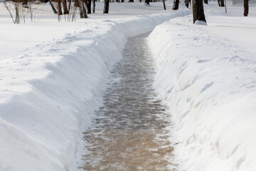 A snow covered path with a small ditch in the middle