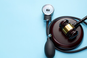 Closeup of judge gavel and stethoscope on a blue background with copy space.