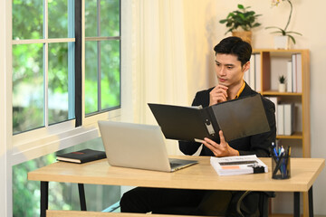 Handsome male account manager checking reports at his office desk