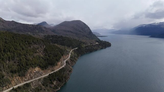 Patagonia argentina seven lakes route road trip winding along lake lacar under cloudy sky, drone aerial footage