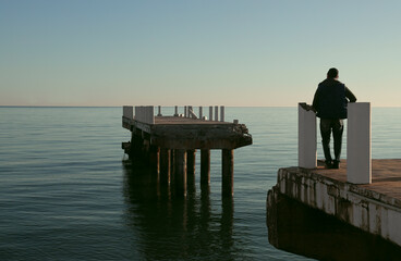 Man in front of a broken bridge. back rear view of Male on broken concrete pier staring at Black...