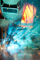 Welder uses torch to make sparks during manufacture of metal equipment, industrial professional worker