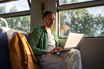 Businessman works on laptop during morning commute on train, remote freelance with WiFi in public...