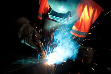 Welder uses torch to make sparks during manufacture of metal equipment, industrial professional worker