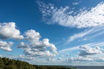Obraz premium A clear blue sky with puffy gray clouds and a few wispy cirrus clouds in the distance, blue sky, landscape