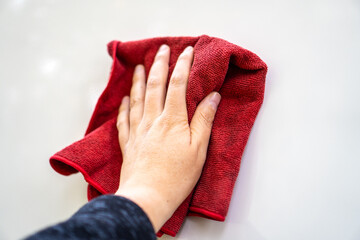 Hand of a man holding a red rag and cleaning a car. Hand washing a white car.