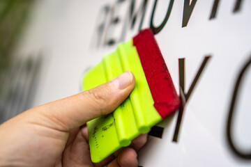 A person installing foil stickers on a car. Applying the sticker with a plastic spatula.