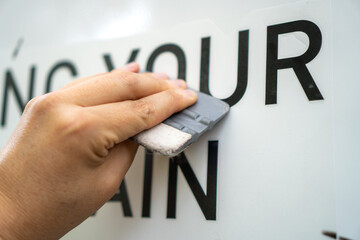 A person installing foil stickers on a car. Applying the sticker with a plastic spatula.