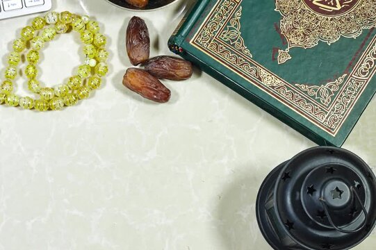 eid concept. lantern and muslim book with Arabic calligraphy Quran - translation : the noble book of Muslims around the world and dates fruit , rosary muslim and keyboard
