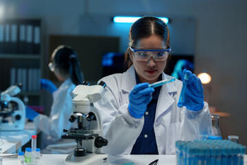 Asian female scientist holds a test tube filled with blue liquid in the laboratory. Examination....