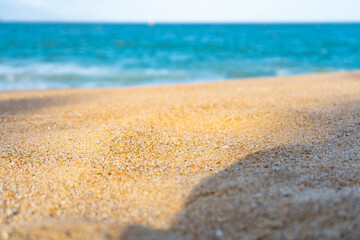 Close-up view of a sandy beach with a blurred turquoise sea in the background. The central part of the image is perfect for placing objects or text. A great choice product showcase