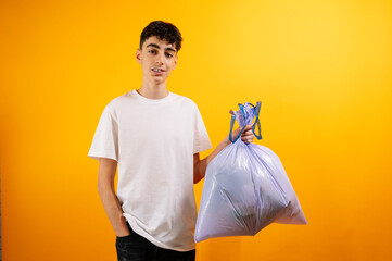 Teenager holding a purple trash bag, smiling.
