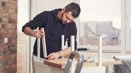 Man working and assembling furniture in a new apartment.