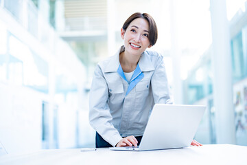 オフィスでパソコン仕事をする作業着を着た女性