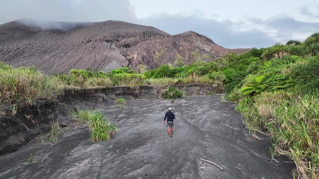 Lone Traveler walking on volcanic ash. Smoke from active volcano background. Tanna Island, drone.