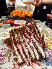 Slice of Layered Cake with Festive Gathering in Background, Vertical Close-Up
