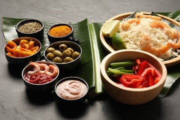 Piece of banana leaf with different food, spices and sauce on grey table, closeup. Healthy eco serving