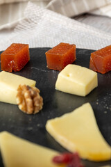 A gourmet cheese platter featuring a variety of cheeses, walnuts, and cranberries artfully arranged on a slate board, ideal for elegant gatherings and celebrations.