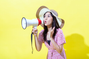 Asian woman wearing a straw hat and a pink floral dress, holding a megaphone with a surprised...
