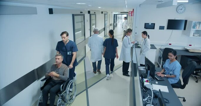 Male and Female Medical Professionals Navigate a Hospital Corridor and Registration Area, Having Healthcare Conversations. Nurse Assists a Patient in a Wheelchair. High Angle Security Camera Footage