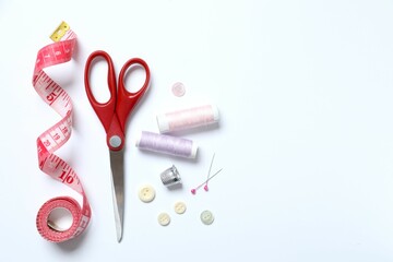 Flat lay composition with different sewing supplies on white background