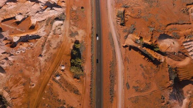 Drone shot captures a truck moving through a Mars-like landscape in the Australian Outback, passing abandoned opal mines amidst the barren, red earth.