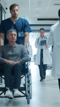 Vertical Screen: Medical Staff Walking Down a Hospital Hallway, Each Headed Towards Different Departments. Caucasian Female Doctor Discussing Treatment Plans, Reviewing Patient Charts on a Tablet