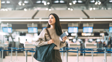 Woman passenger holding passport and boarding pass to transit at international airport terminal for...