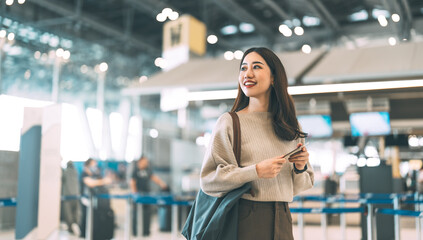Woman passenger holding passport and boarding pass to transit at international airport terminal for...