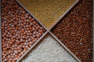 A set of grain cereals. Rice, buckwheat and millet groats in a wooden tray. A grocery set of cereals. Import of grain.