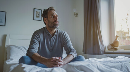 Obraz premium A man sits indoors, holding her head with a look of frustration and deep thought,