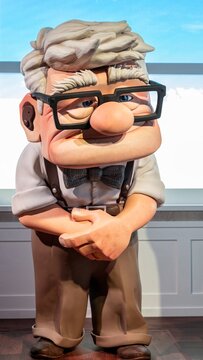 Madrid, Spain; 05-14-2024: Large figure of the character Carl Fredricksen, the old man from the animated movie Up, holding his cane with both hands in front of the window of his house in an exhibition